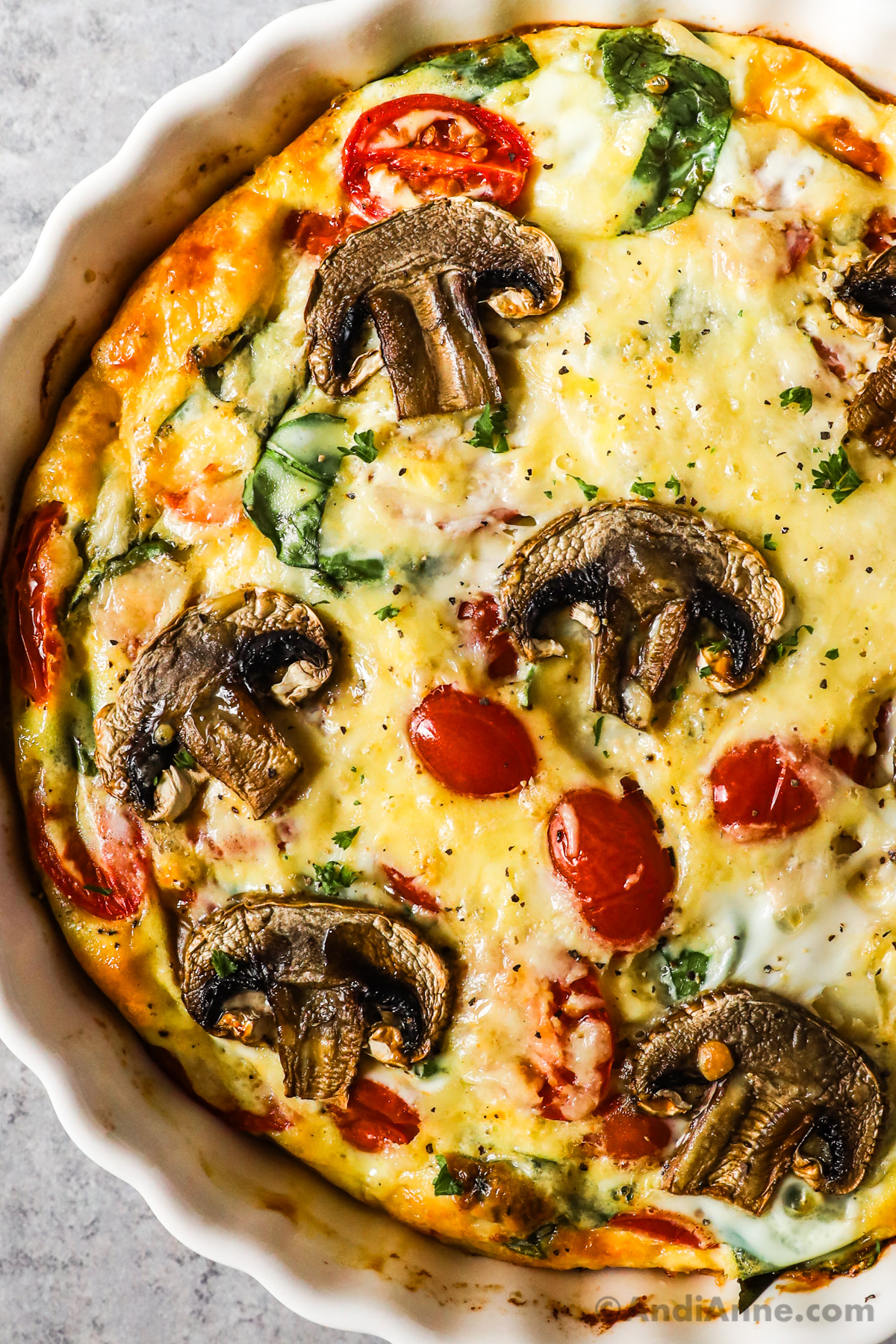Close up of cooked mushrooms, tomatoes and spinach inside a frittata