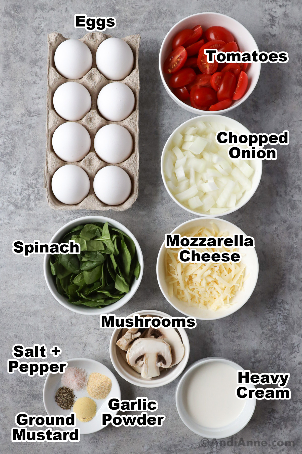Eggs, bowls of chopped tomatoes, onion, spinach, shredded mozzarella, mushrooms, heavy cream, and spices.