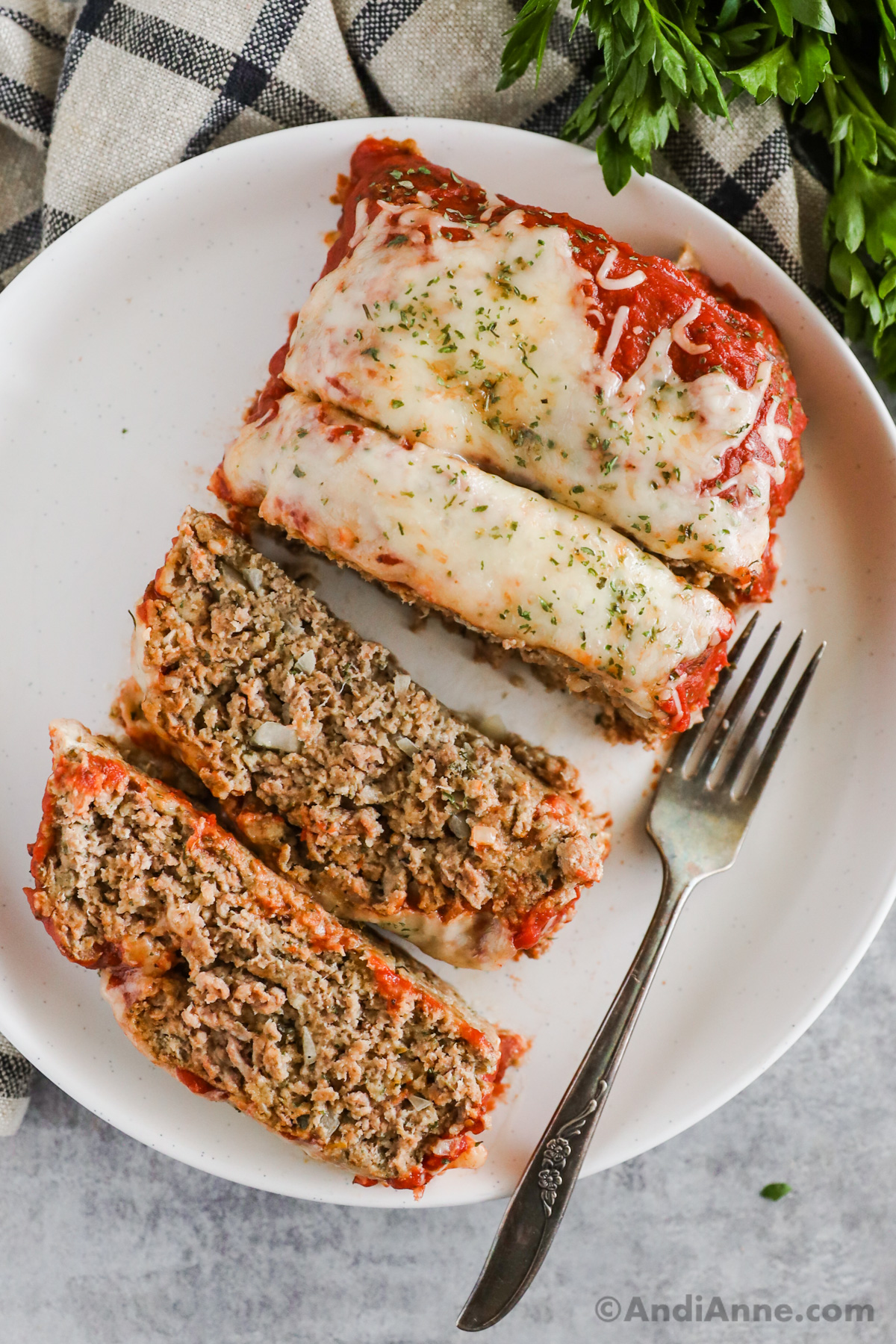 Slices of pizza meatloaf on a white plate with a fork.