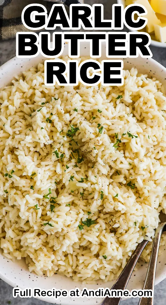 A bowl with garlic butter rice and two spoons.