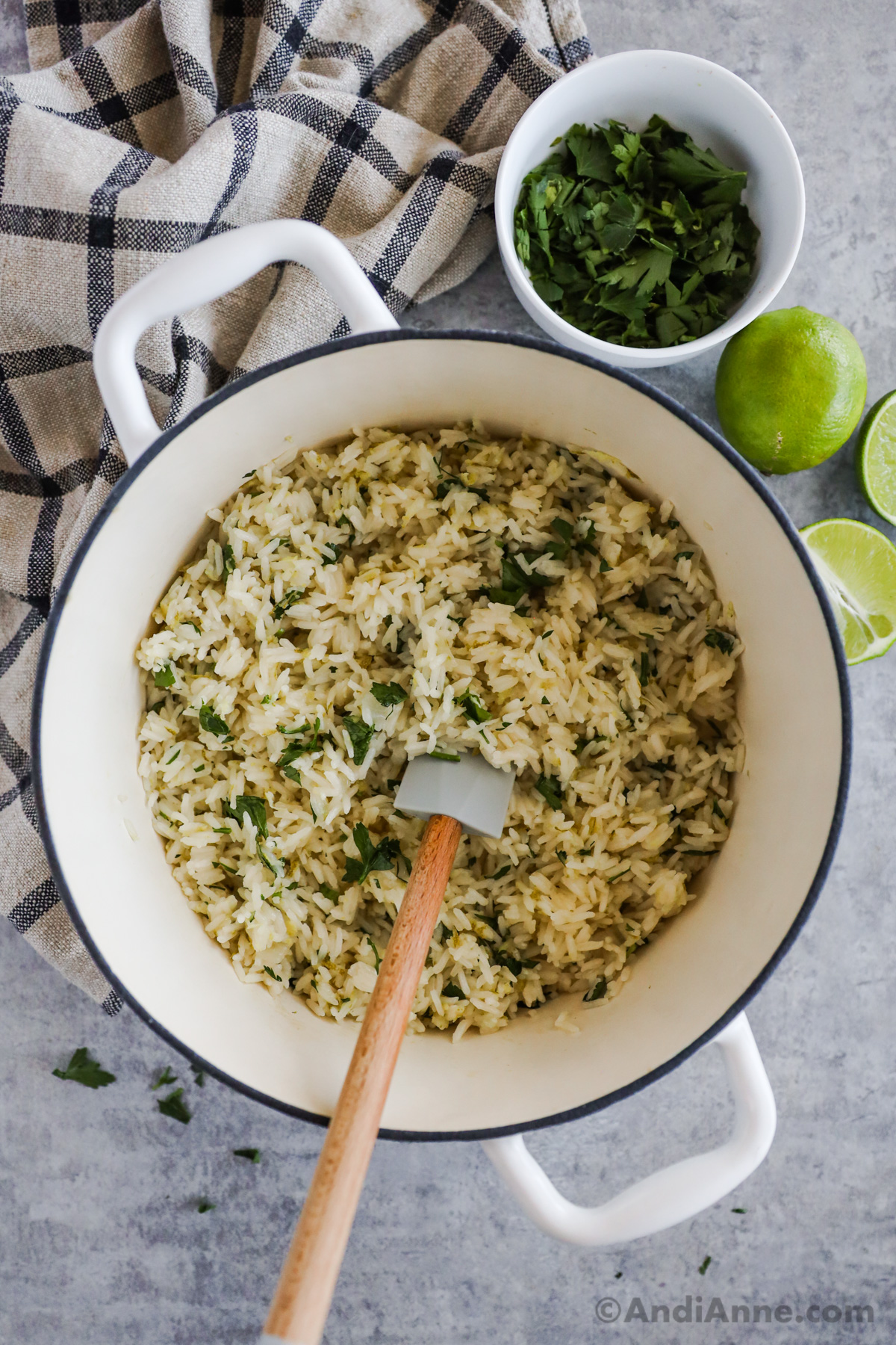 A pot of cilantro lime rice with a spatula and fresh limes around the pot.