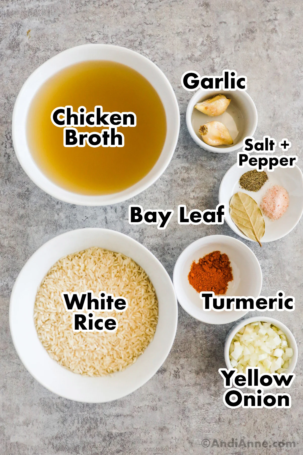 Recipe ingredients on the counter including bowl of chicken broth, bowls of uncooked rice, garlic cloves, and spices.