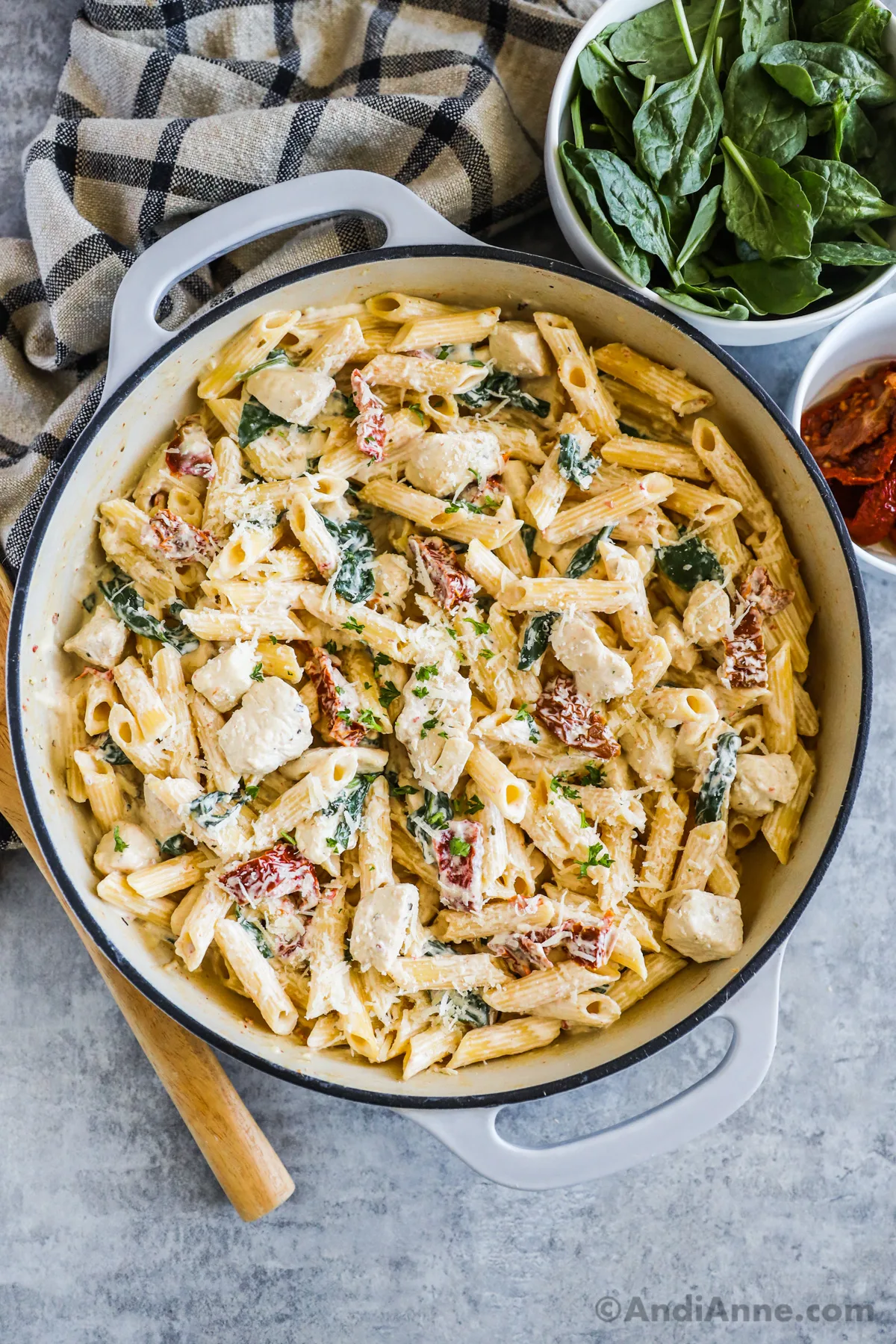 A pot of tuscan pasta in a creamy sauce with sun dried tomatoes and spinach. 