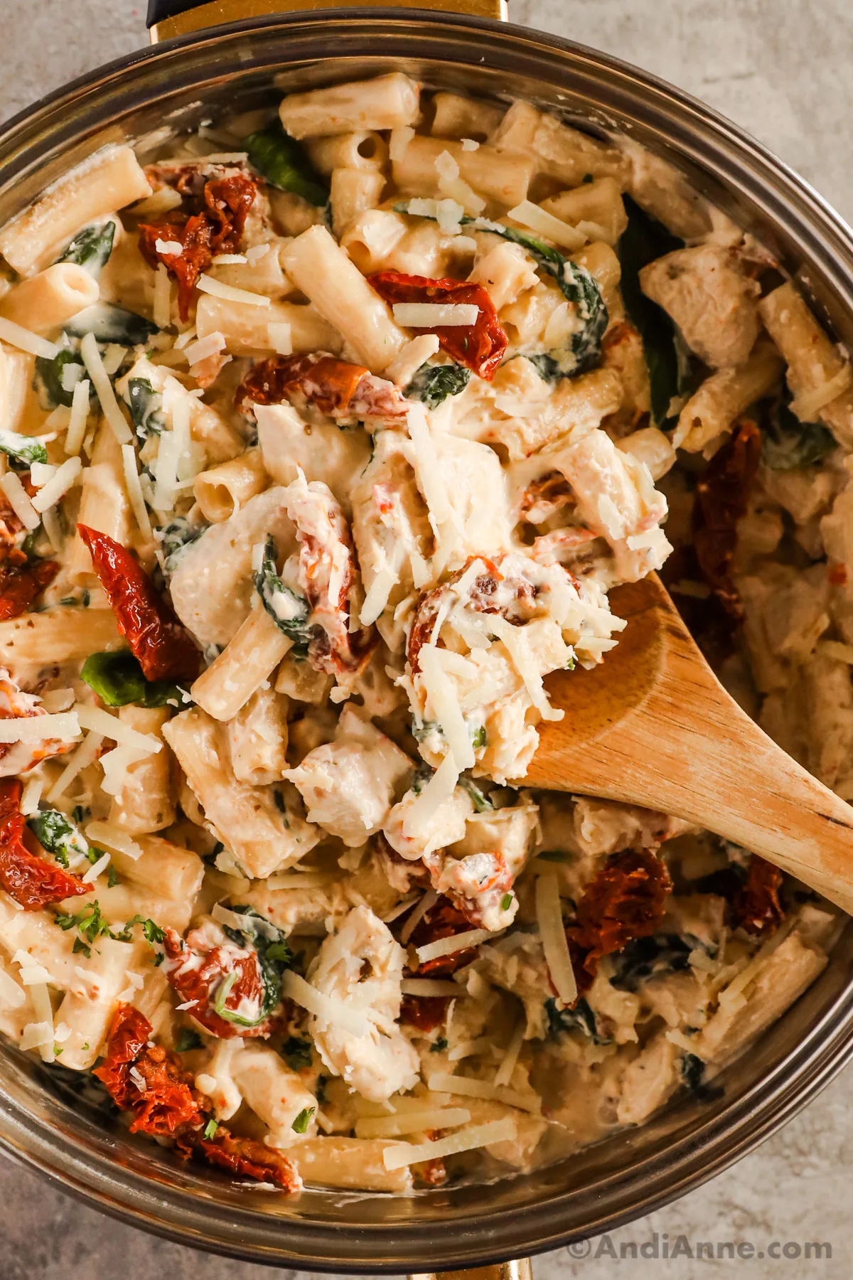 Close up of a spoon scooping tuscan chicken pasta recipe. 