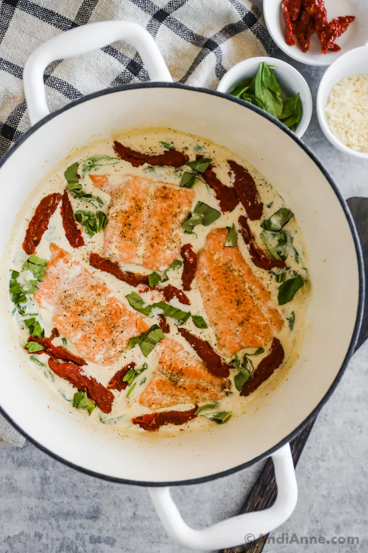 A white pot of tuscan salmon recipe with spinach, sun dried tomatoes all in a creamy sauce.