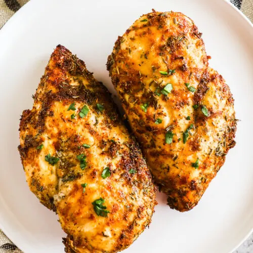 Cooked air fryer chicken breasts on a white plate.