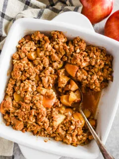 A white dish with apple crisp recipe and a spoon.