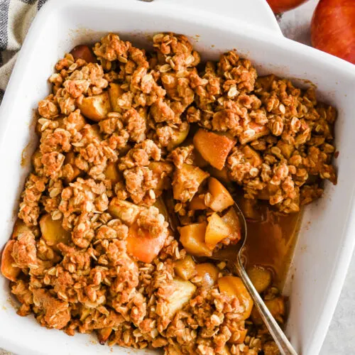 A white dish with apple crisp recipe and a spoon.