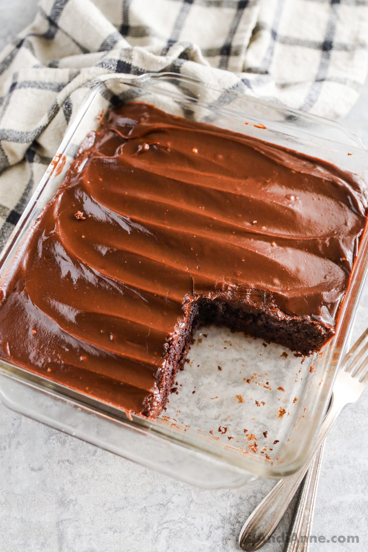 Chocolate wacky cake in a glass baking dish with a slice cut out of it. 