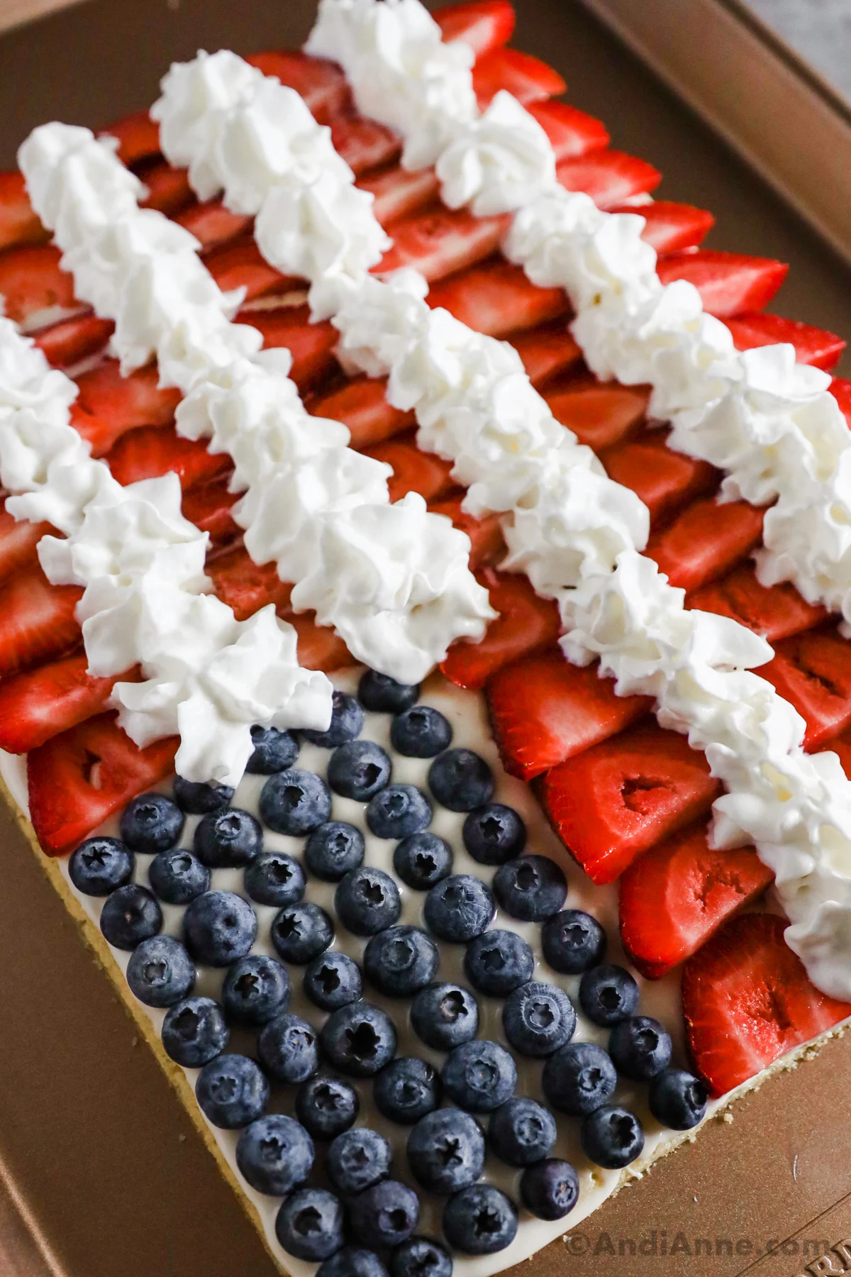 Close up of blueberries, sliced strawberries and whipped cream on flag fruit pizza.