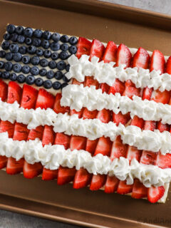 American flag fruit pizza on a sugar cookie crust created from sliced strawberries and blueberries.