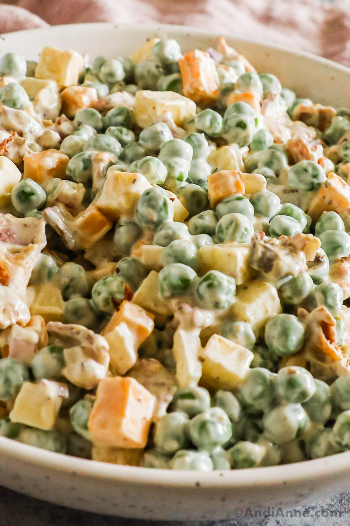 Close up of peas, cheese, and bacon in a creamy sauce to make pea salad.