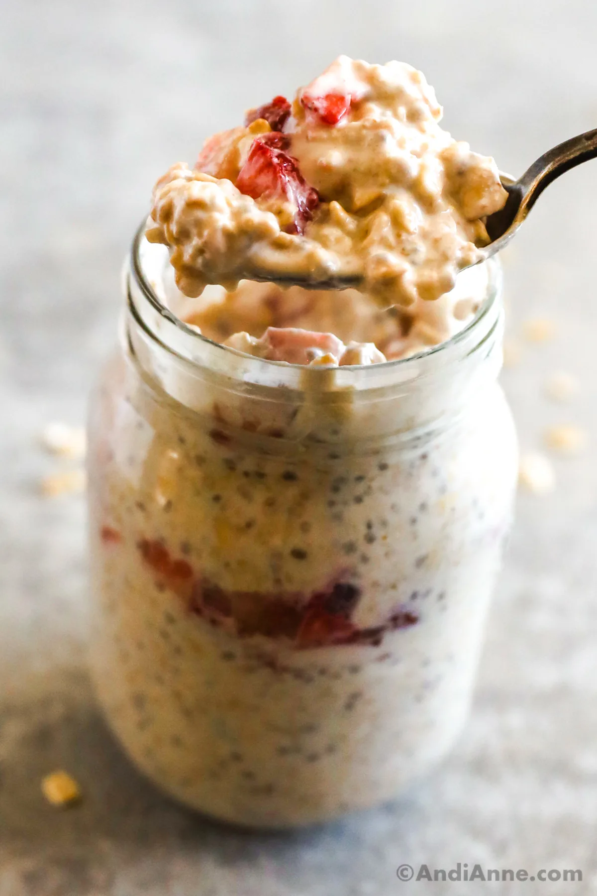 A spoon scooping overnight oats out of a mason jar. 