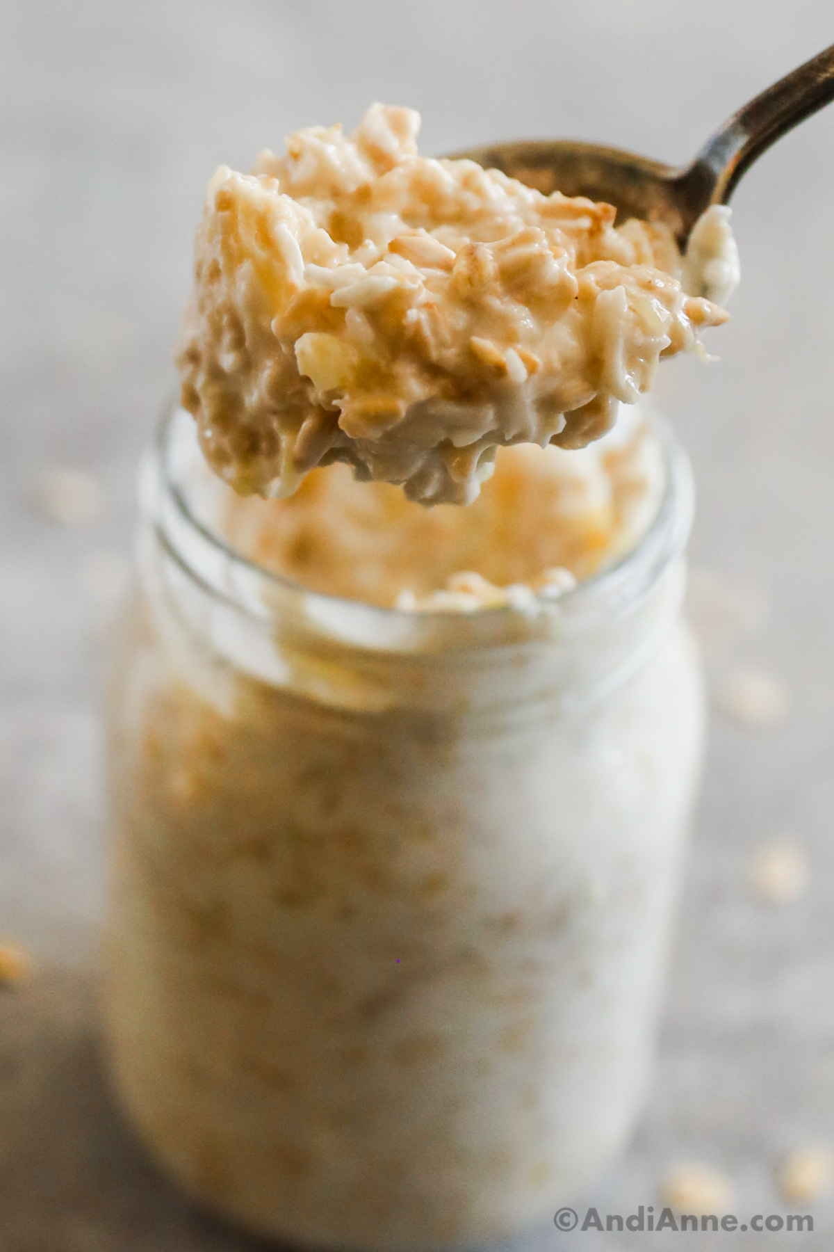 A spoonful of banana bread overnight oats with a mason jar of oats in the background.