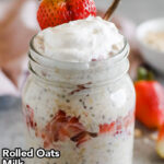 A mason jar with strawberry cheesecake overnight oats topped with yogurt and a sliced strawberry. Made with rolled oats, milk, plain yogurt, strawberries, graham crackers, cream cheese, honey and vanilla extract.
