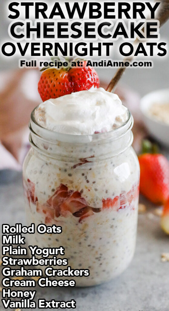 A mason jar with strawberry cheesecake overnight oats topped with yogurt and a sliced strawberry. Made with rolled oats, milk, plain yogurt, strawberries, graham crackers, cream cheese, honey and vanilla extract.