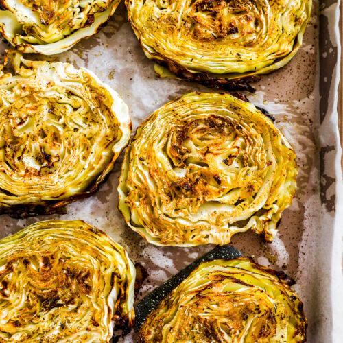 Roasted cabbage steaks on a baking sheet.