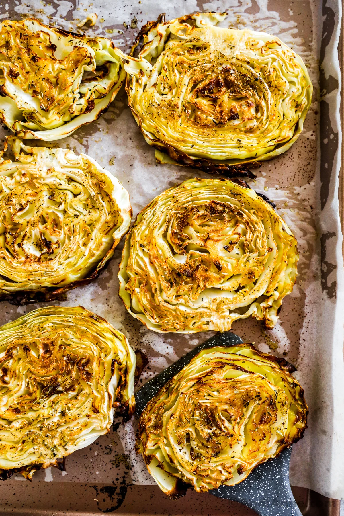 Close up of roasted cabbage steaks on a baking sheet.