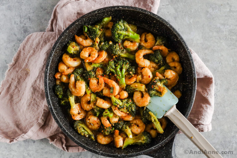 Shrimp and broccoli in honey garlic sauce in a frying pan with a spatula.
