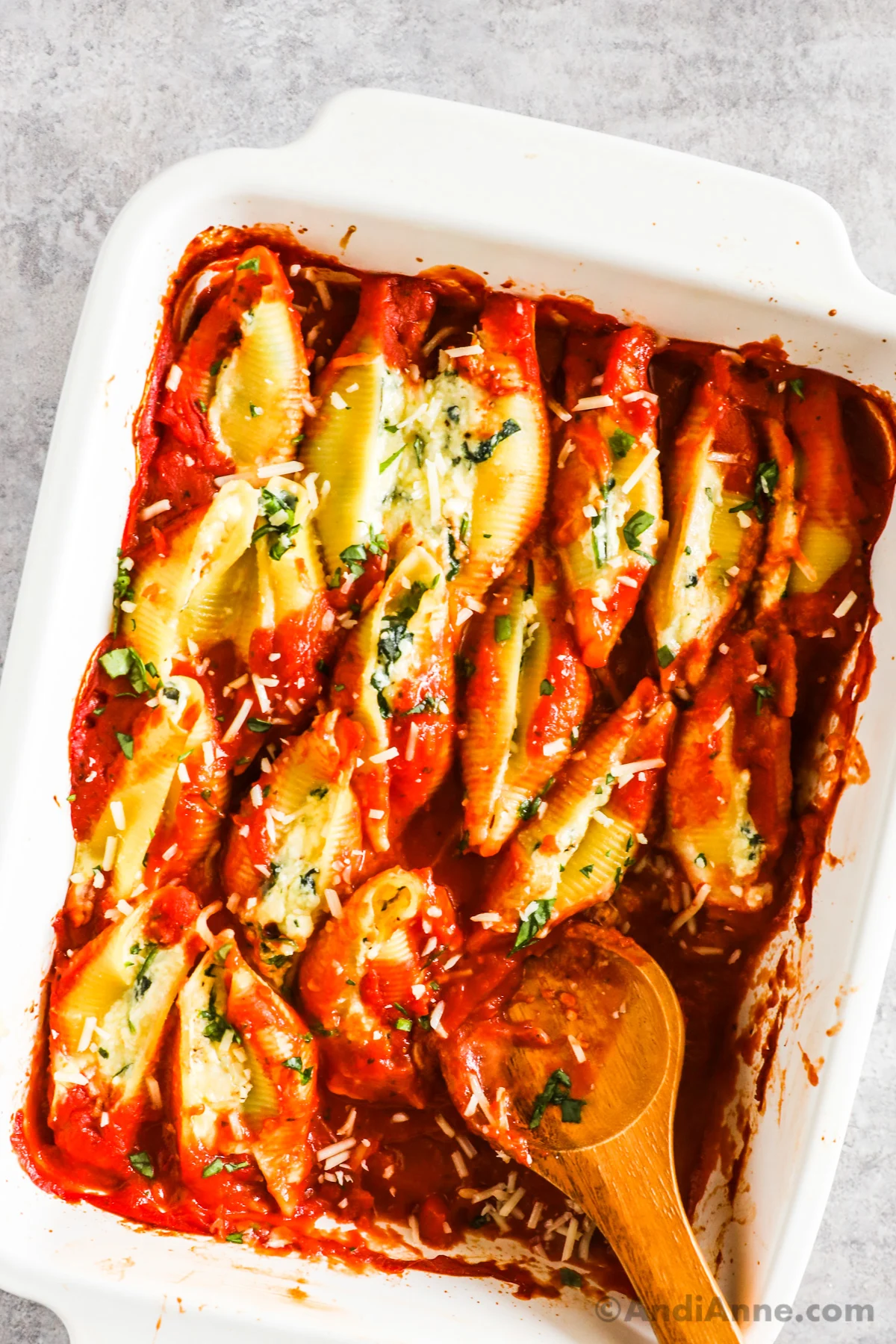 A baking dish with spinach ricotta stuffed shells in marinara sauce.