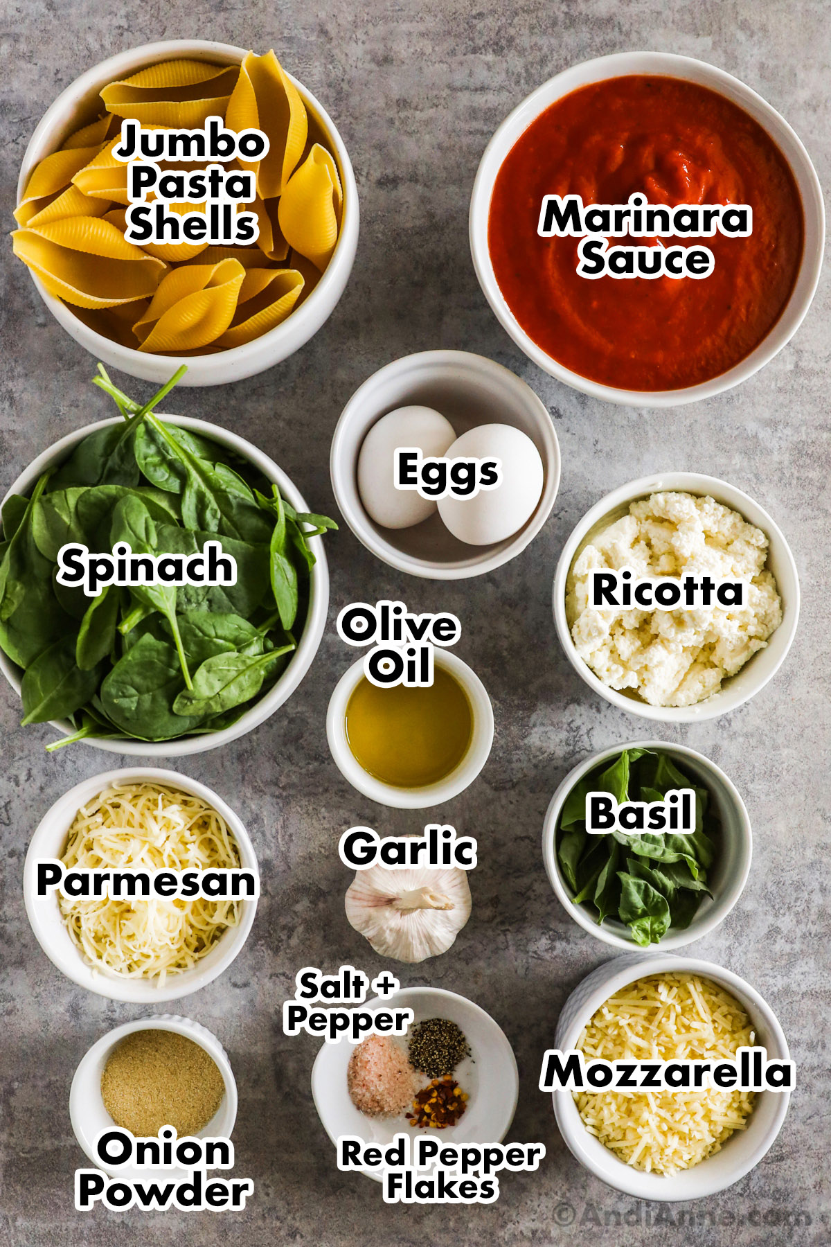 Recipe ingredients including bowls of spinach, jumbo pasta shells, marinara sauce, eggs, ricotta, olive oil, parmesan, basil, mozzarella, and spices.