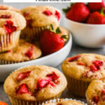 Close up image of fresh strawberry muffins with fresh strawberries surrounding them.