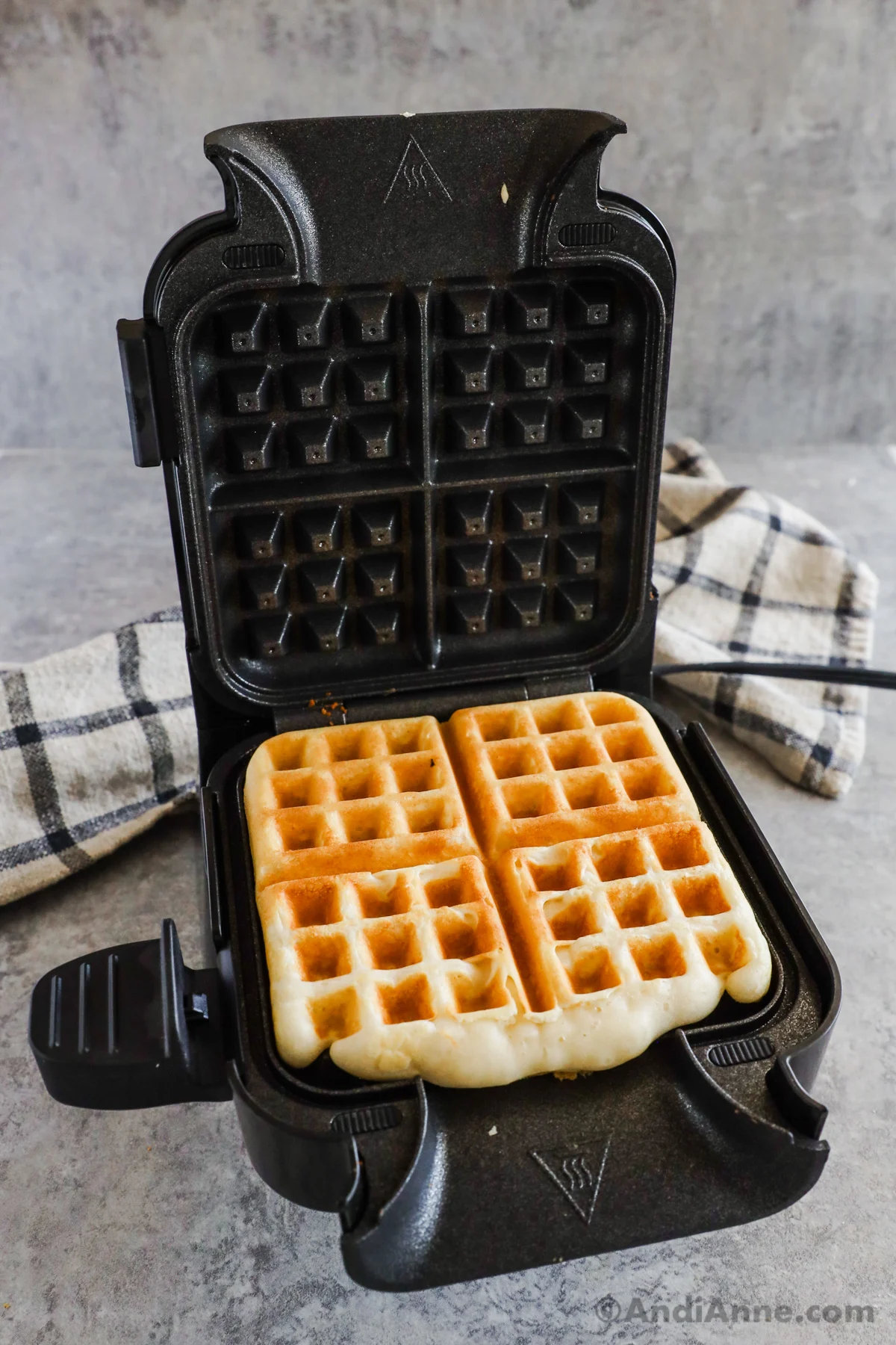A waffle iron with a cooked classic waffle recipe inside.