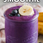 A glass of blueberry banana smoothie with fresh blueberry and banana slice topping.
