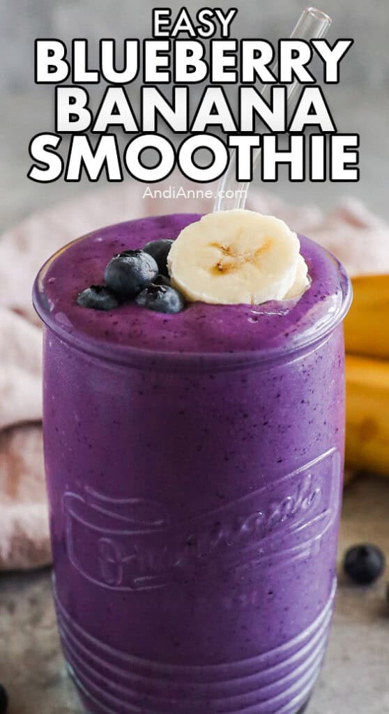 A glass of blueberry banana smoothie with fresh blueberry and banana slice topping.