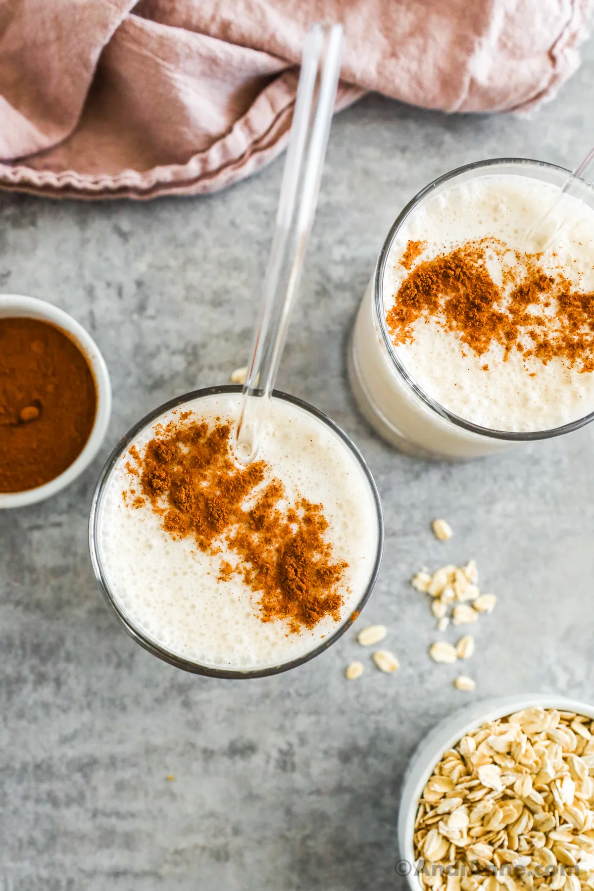 Looking down at two glasses with cinnamon breakfast smoothie, sprinkled with cinnamon. 