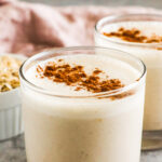 A glass of cinnamon bun breakfast smoothie sprinkled on the top with cinnamon.