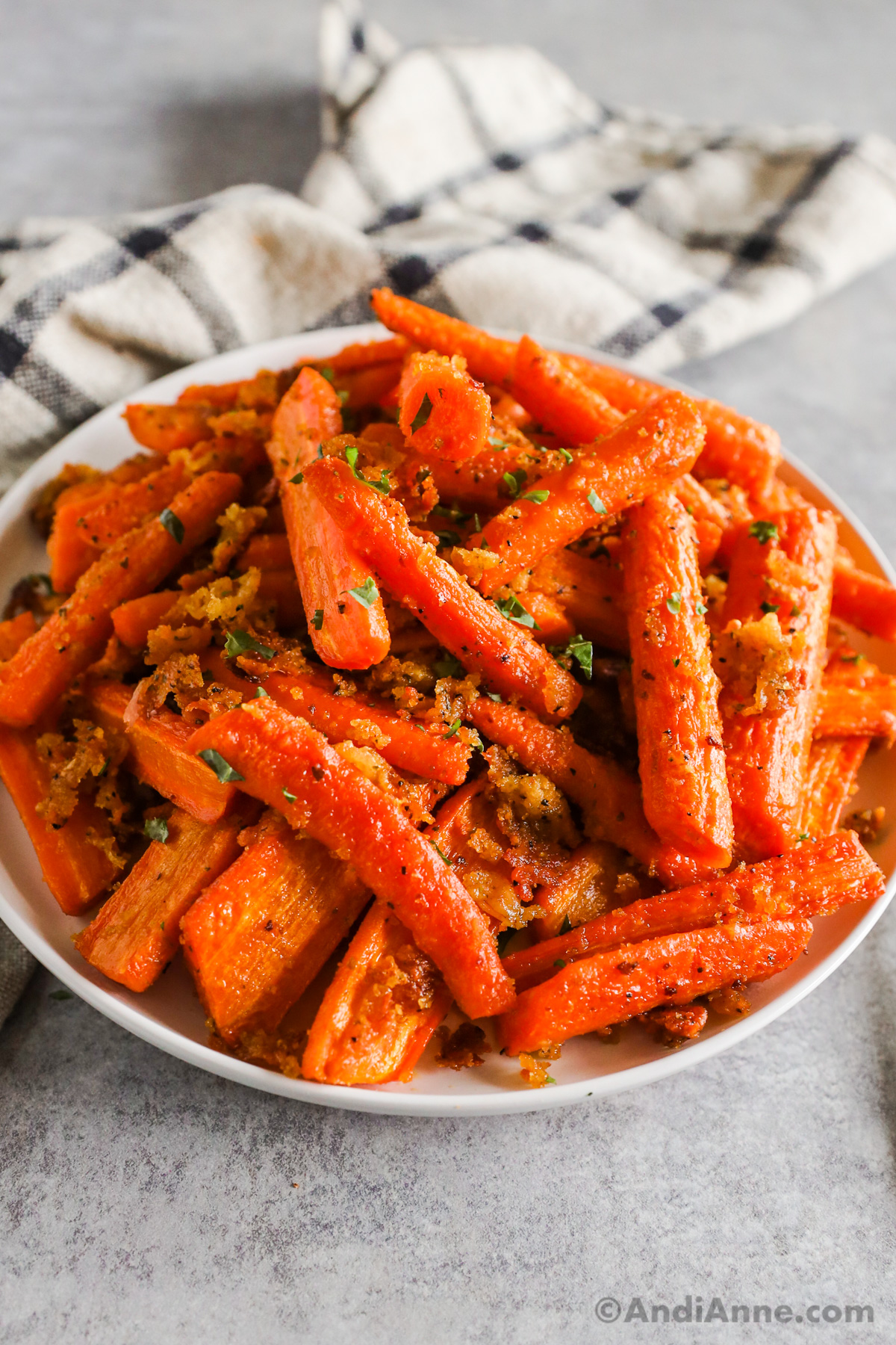Roasted carrots with parmesan and bread crumbs on a white plate.