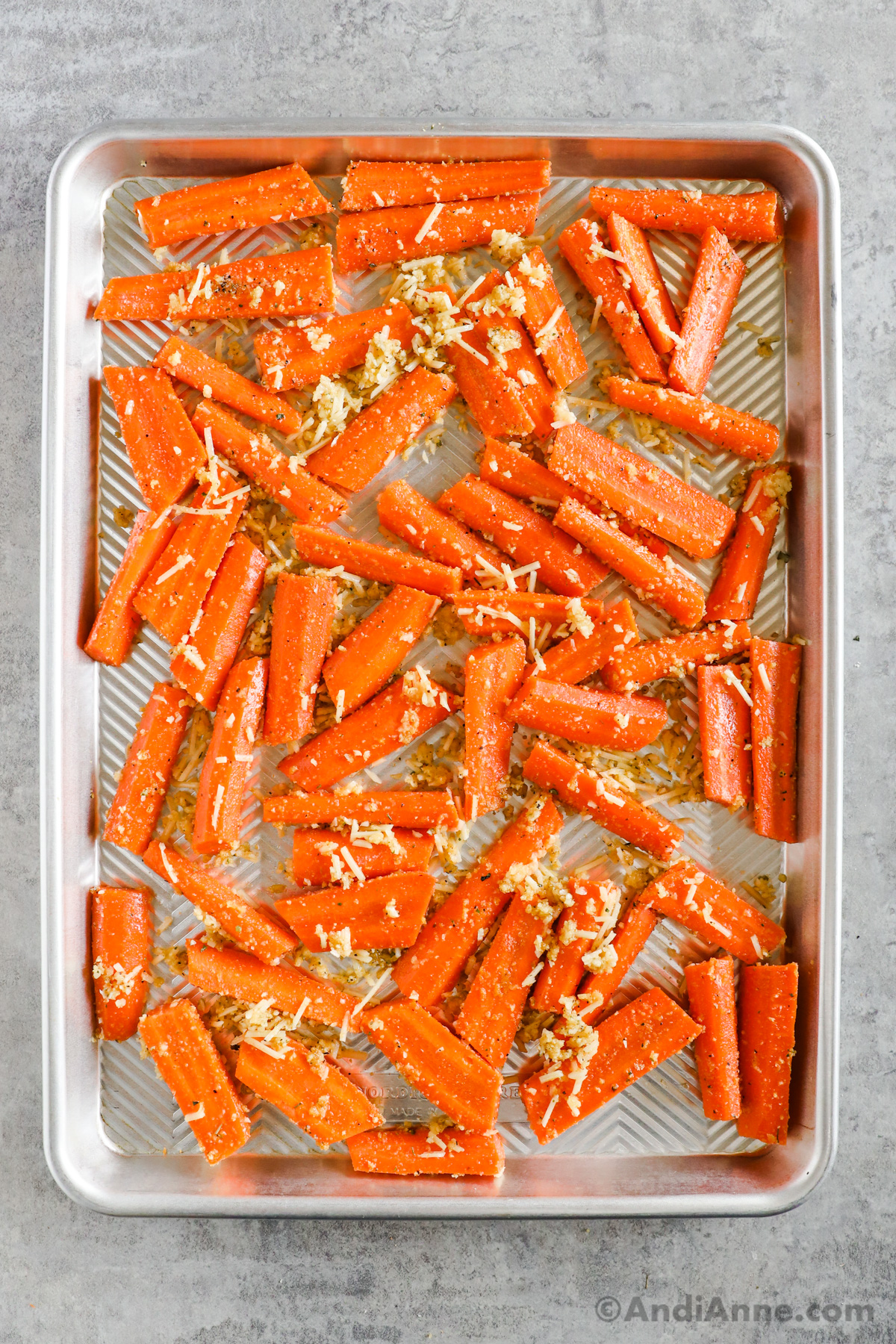 Sliced carrots and parmesan cheese on a baking sheet.