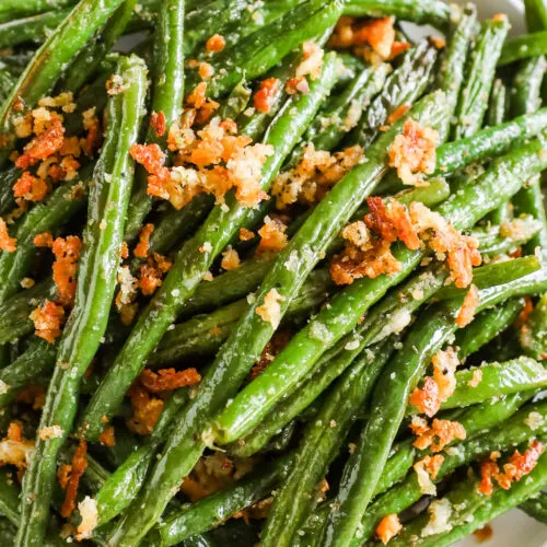 Close up of garlic parmesan green beans with crunchy bread crumbs on a plate.