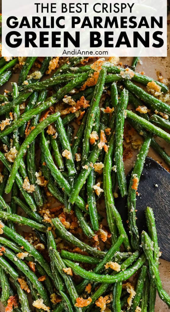 Roasted green beans with parmesan on a baking sheet with a wood spatula.