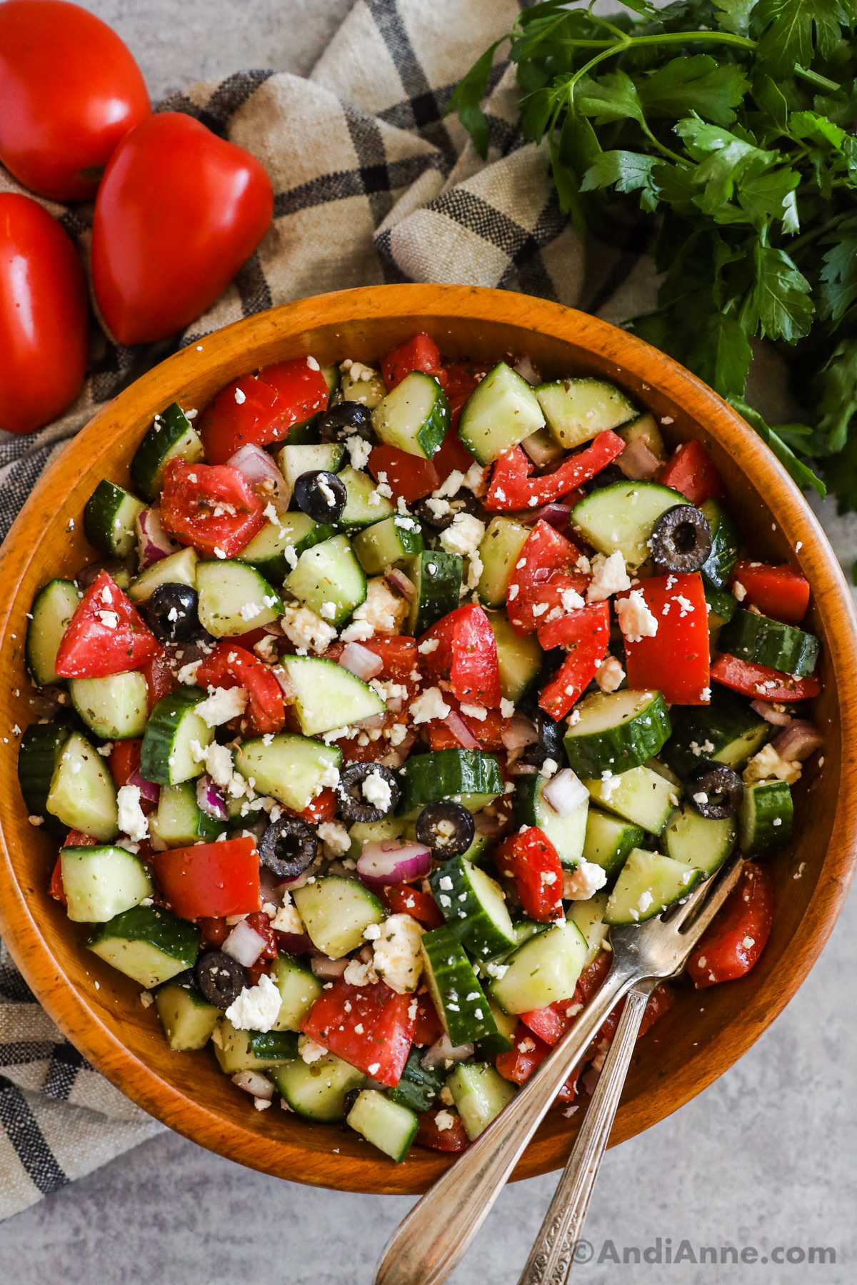 A bowl of greek cucumber salad with tomato, onion and olives.