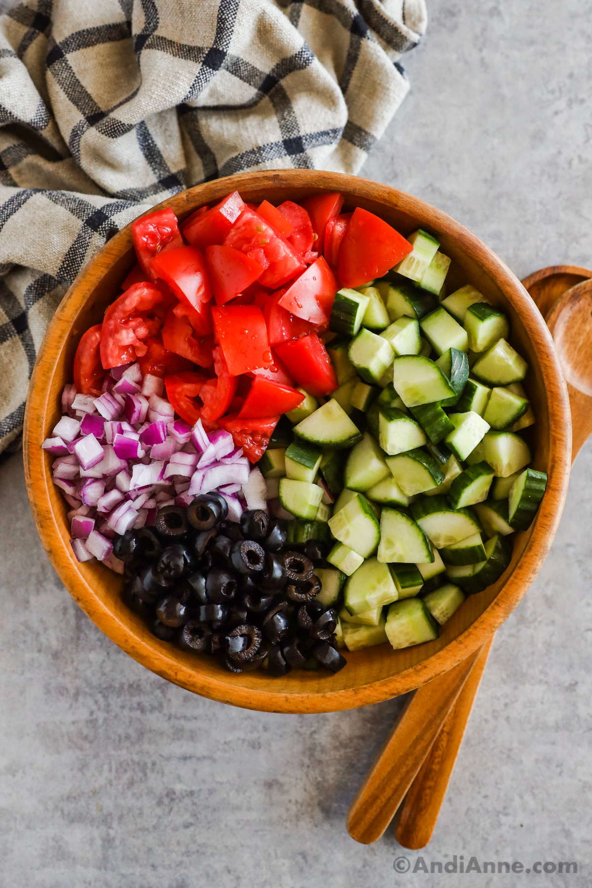 Bowl of chopped cucumber, tomatoes, red onion, sliced olives.