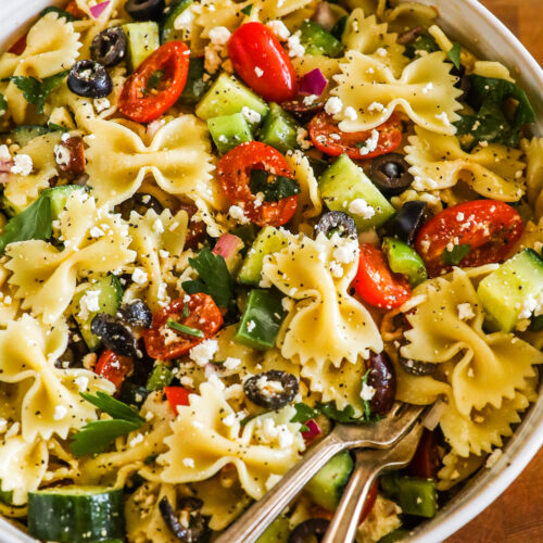 a bowl of greek pasta salad with bowtie pasta noodles.