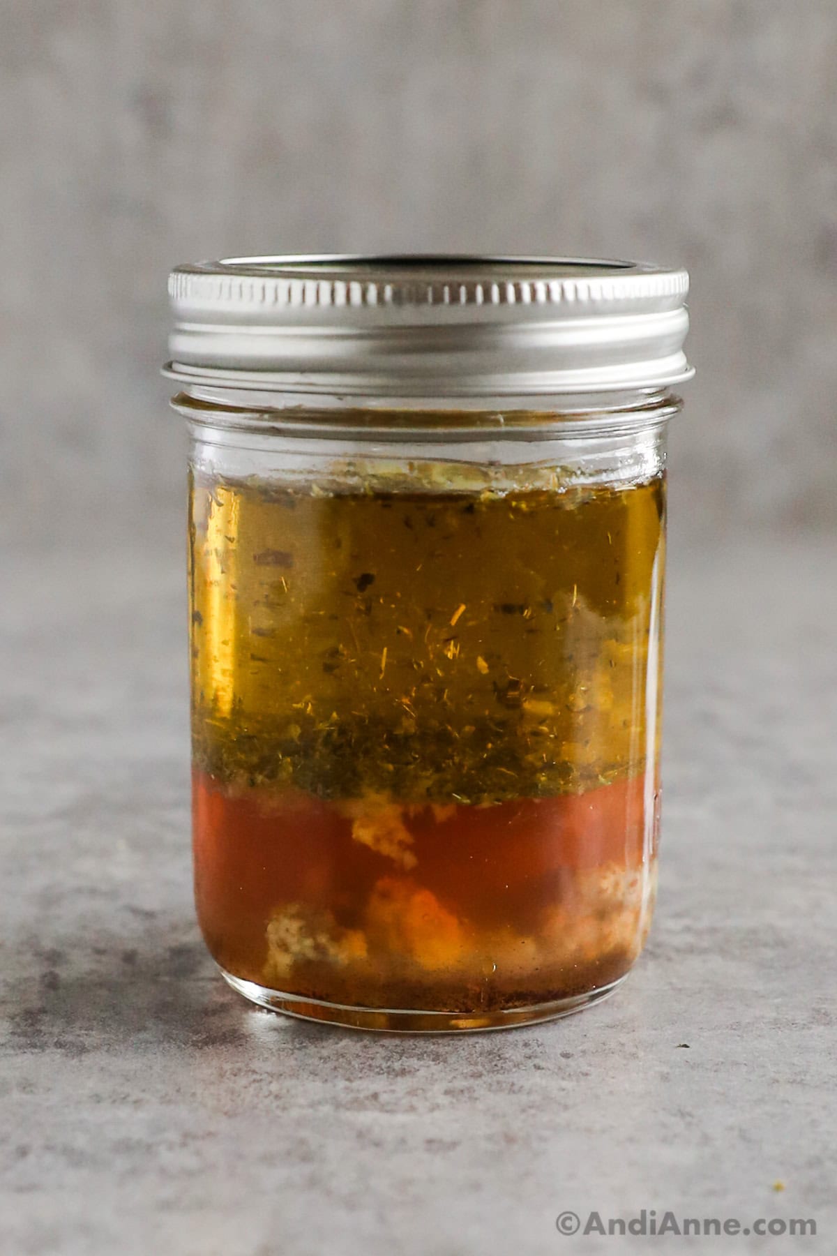 A mason jar with greek salad dressing recipe.