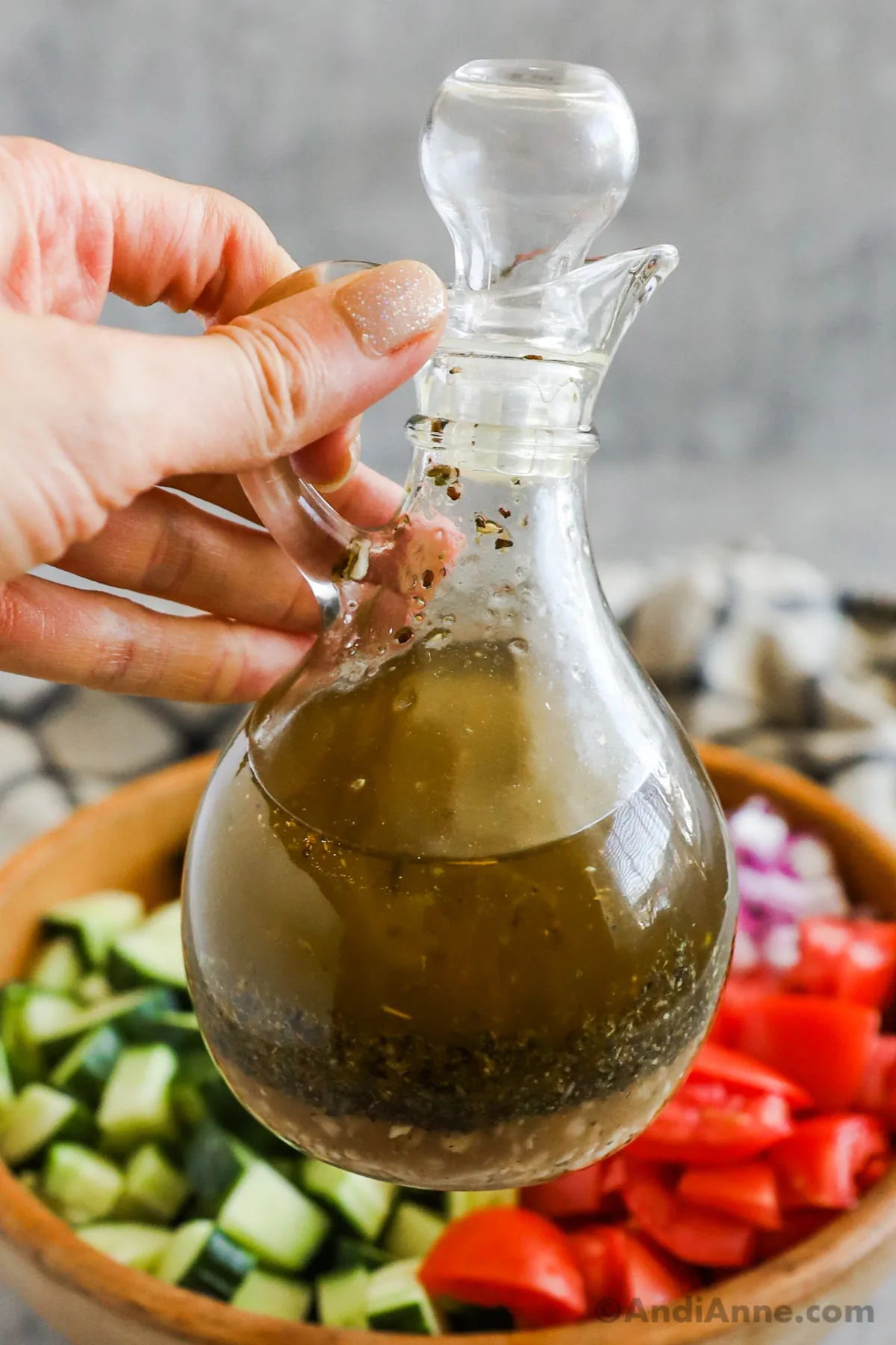 A hand holding a jar of homemade italian dressing.