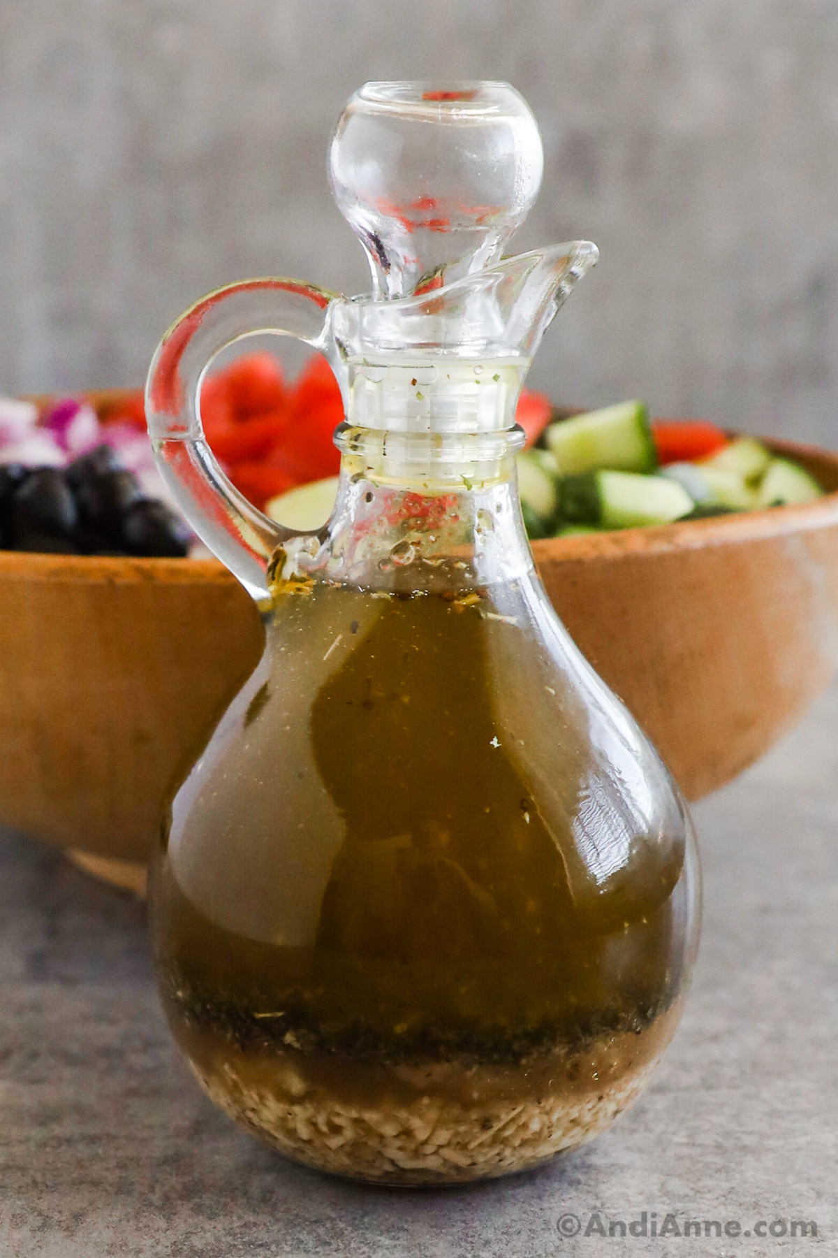 A jar of Italian salad dressing with a salad in the background.