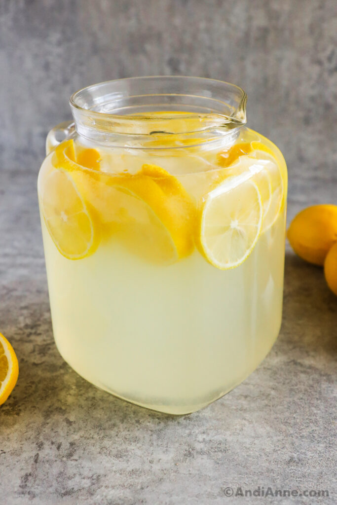 Photo of a glass pitcher of cold lemonade with sliced lemons inside