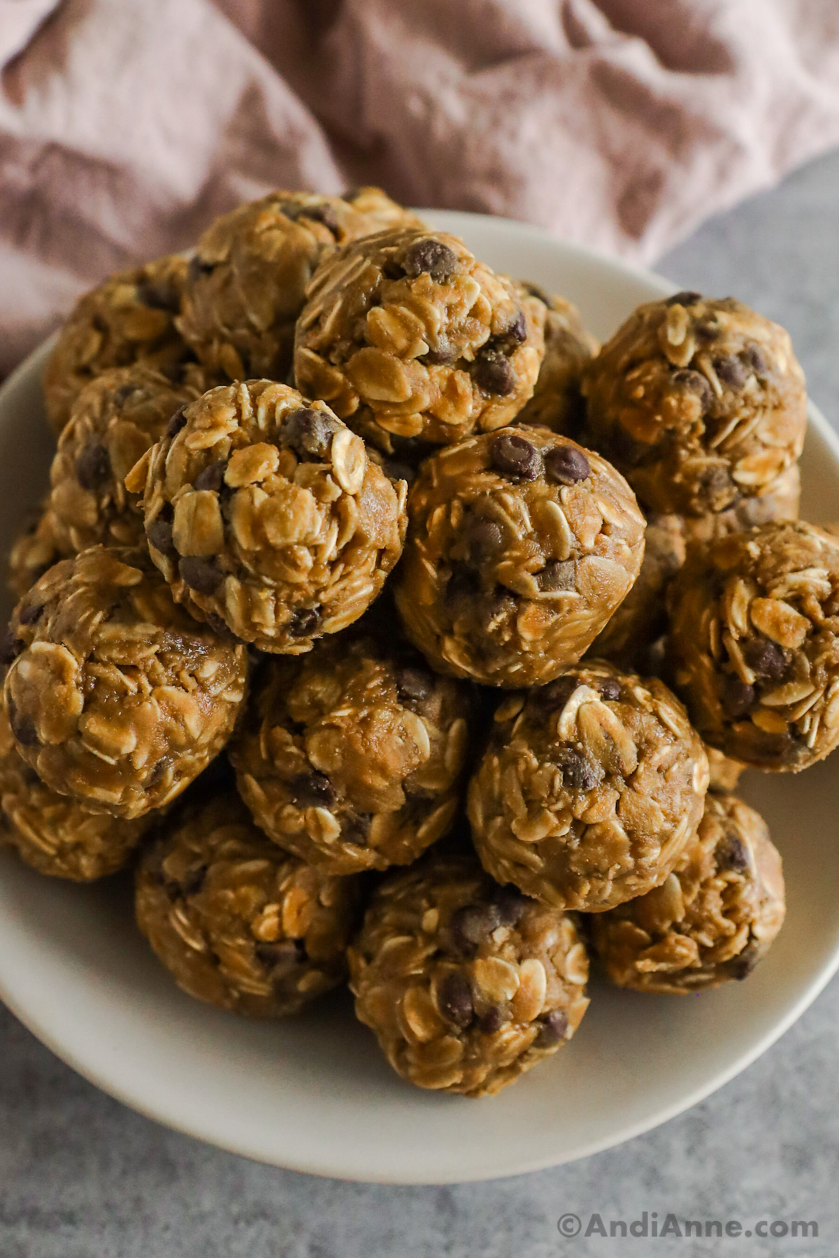 Close up of peanut butter oat balls with chocolate chips, stacked on a plate.