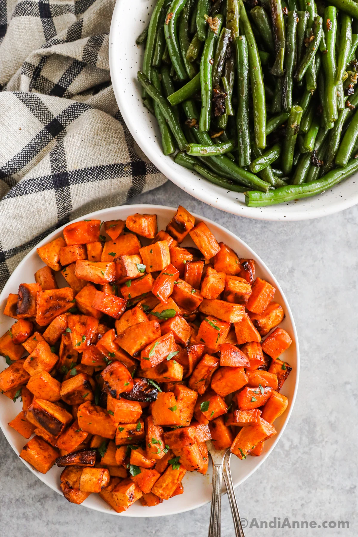 A bowl of cubed honey cinnamon roasted sweet potatoes and a bowl of sauteed green beans.