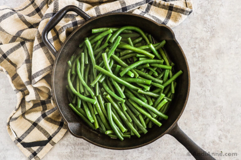 Green beans steaming in water in a skillet.