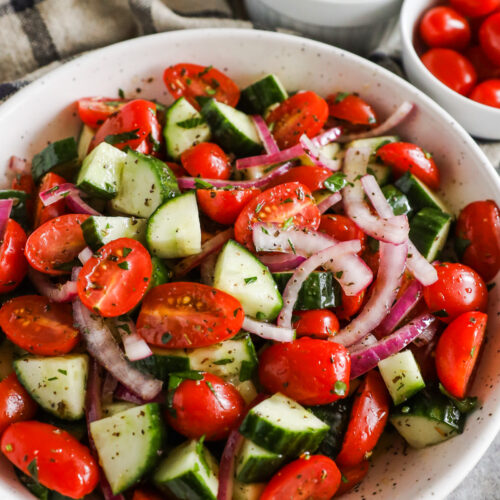 Cucumber tomato salad recipe in a bowl with sliced red onion.