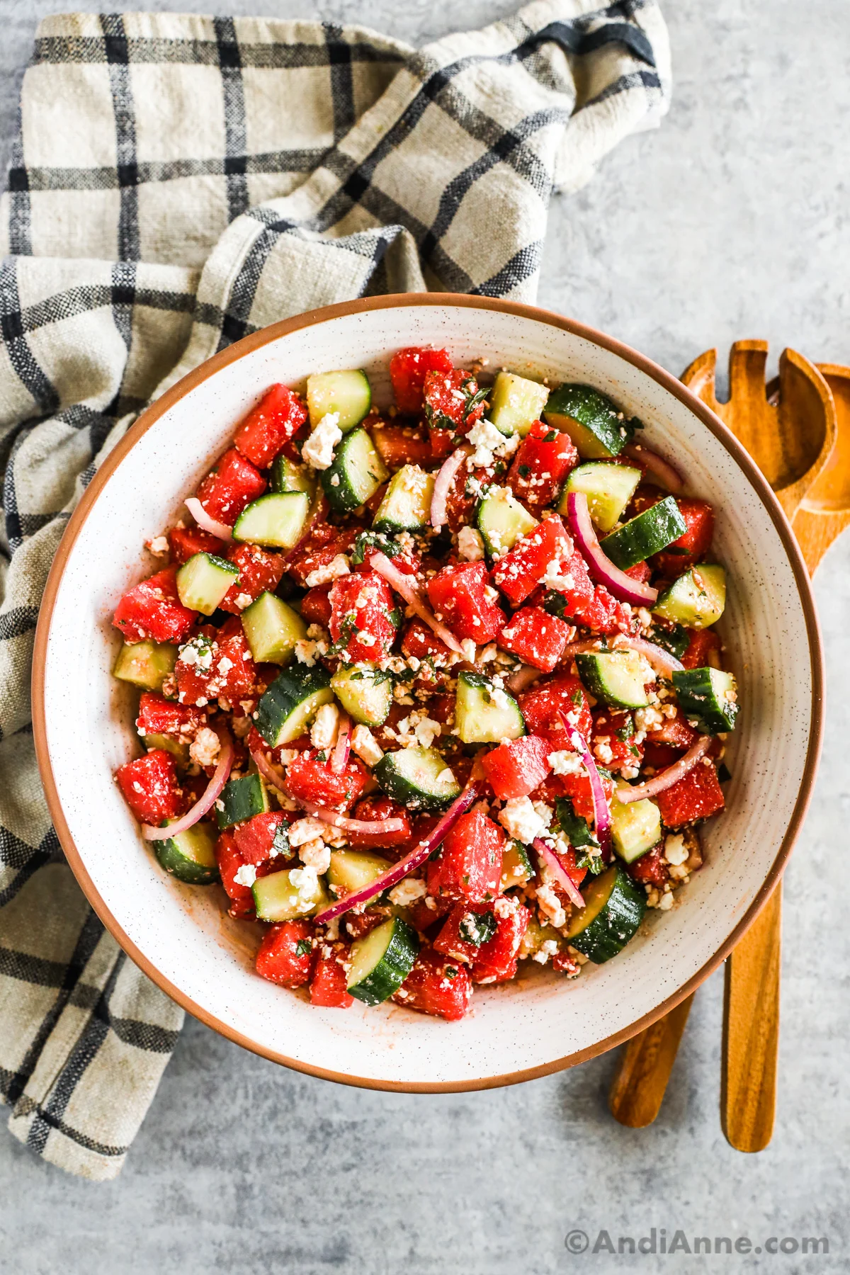 Watermelon cucumber salad in a large bowl with sliced onion and feta cheese.