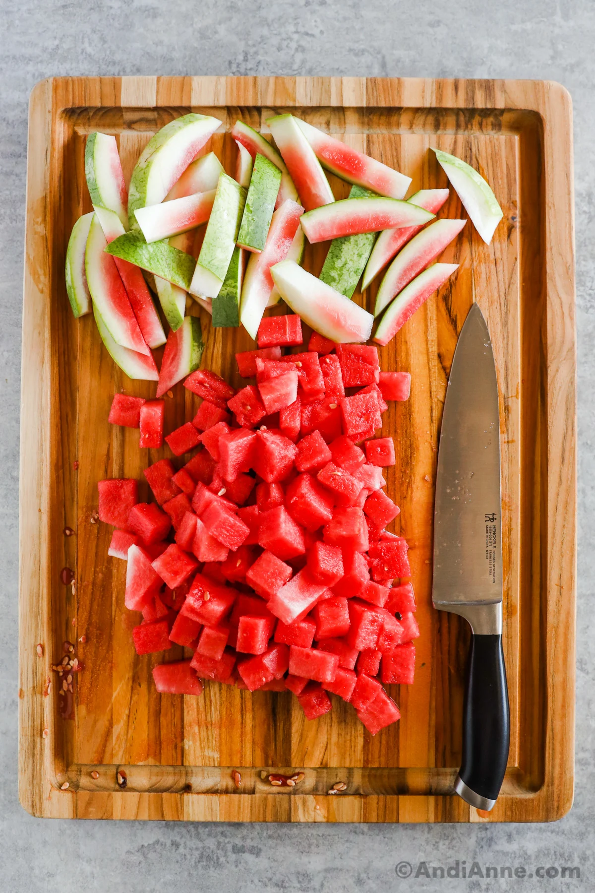 Chopped watermelon on a cutting board with a knife.
