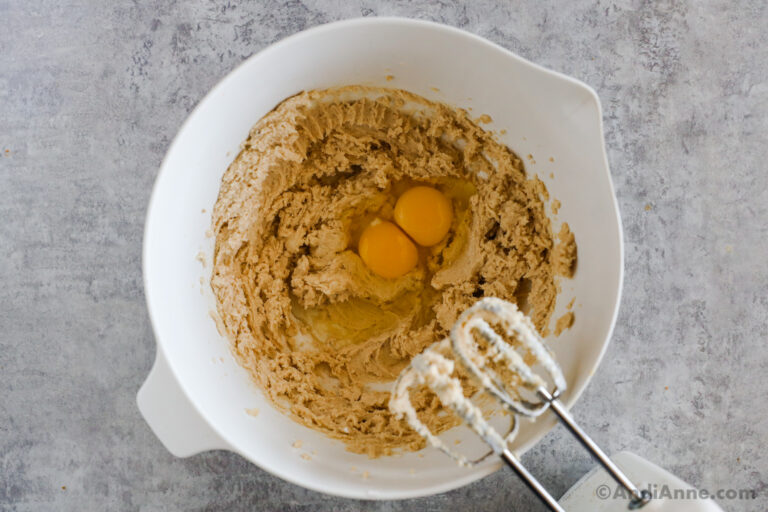 Creamed butter and sugar in a bowl with eggs on top.