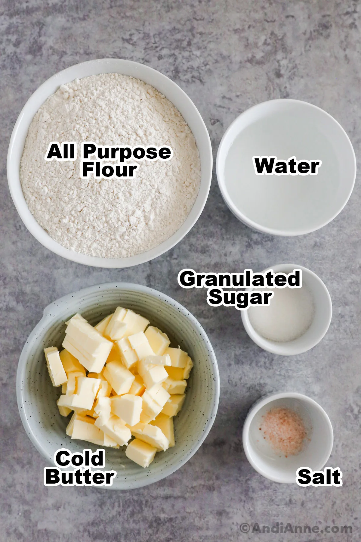 Ingredients on counter including bowl of flour, water, granulated sugar, butter and salt.